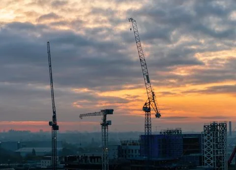Tower Cranes Over Construction Site at Dramatic Sunrise Stock Photos