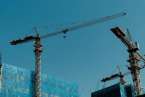 Tower cranes over modern construction site Stock Photos