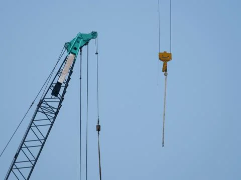 Tower cranes working on a construction site lifts a load at high-rise building Foto stock