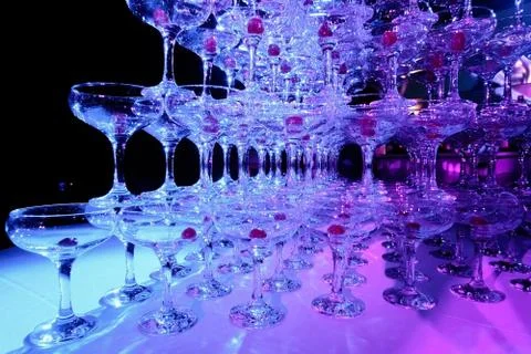 A tower of empty martini glasses with a cherry is on the table. Party at the Stock Photos
