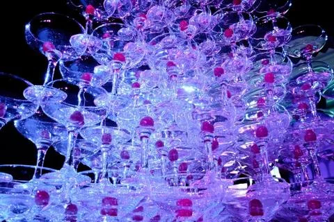 A tower of empty martini glasses with a cherry is on the table. Party at the Stock Photos