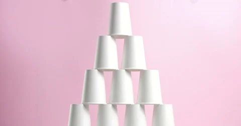 Tower made of white paper cups on pink background Stock Footage 80826281