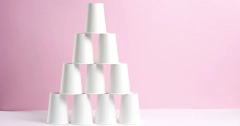 Tower made of white paper cups on pink background Stock Footage 80826353