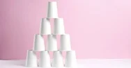 Tower Made Of White Paper Cups On Pink Background Stock Footage