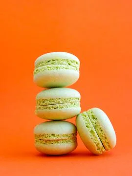 Tower of mint green pastel macarons close-up on bright orange background Stock Photos