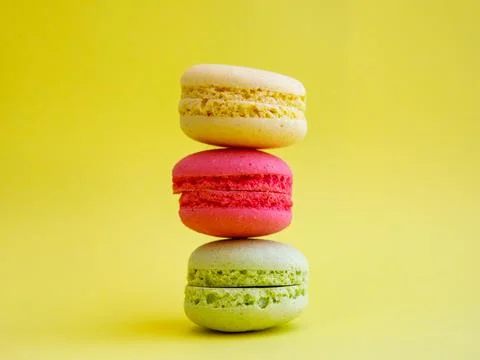 Tower of multi-colored assorted bright macarons close-up on yellow background Foto stock