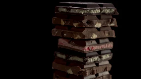 Tower of pieces different chunks of chocolates rotate on a black background Stock Footage 124276757