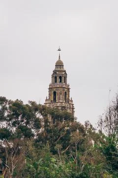 Tower soars over trees in cloudy sky Stock Photos