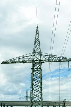 Tower structure supporting power lines under a cloudy sky in a rural area 写真素材