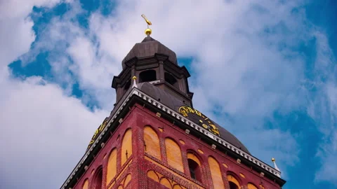 A tower with a weather vane and a clock against a sky with clouds. Video stock 198031985