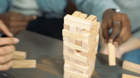 Tower of wooden blocks. Close-up hands of friends playing block removal game Stock Footage 125615657