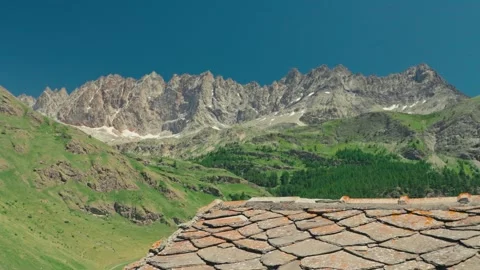 Towering Alpine Mountain Ridge Above Rustic Stone Roof in a Scenic Mountain Stock Footage 341911996