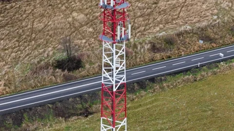 Towering cell structure in white and red, with various antennas, standing a.. Video stock 257663187