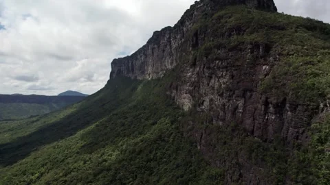 Towering Cliff Face and Lush Green Forest in a Dramatic Landscape Aerial Stock Footage 332727096