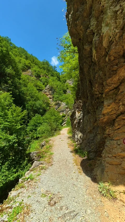 Towering cliffs frame a winding gravel trail. Gradasnica River Canyon, Vertical 스톡 동영상 342327399