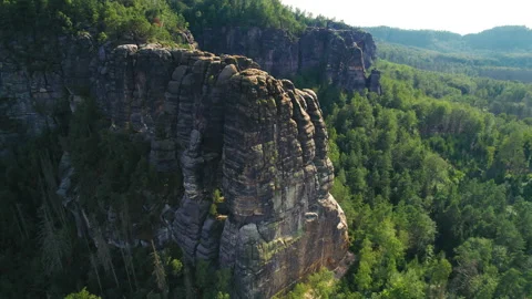 Towering cliffs with rugged formations rise amidst a vast forest, surrounded by Stock Footage 288315154