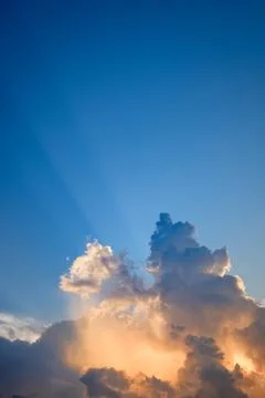 Towering cloudscape and evening sunrays Stock Photos
