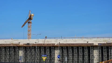 Towering construction building with workers walking on concrete levels A crane Stock Footage 286081193
