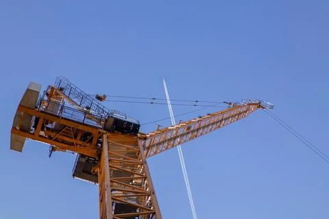 A towering construction crane set against a clear blue sky Stock Photos