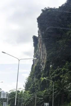 Towering limestone cliffs rise above the tropical landscape near a winding .. Stock Photos