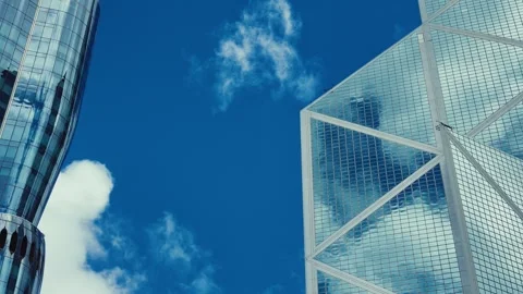 A towering modern skyscraper in Hong Kong with a glass facade reflecting vibrant Stock Footage 338311533
