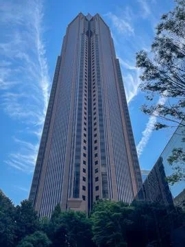 A towering modern skyscraper shot from below against a bright blue sky with.. Foto stock