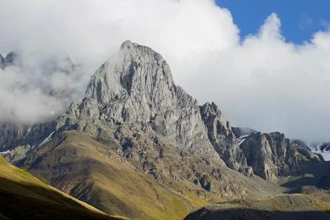 A towering mountain peak rises through the mist in Kazbegi, Georgia Stock Photos