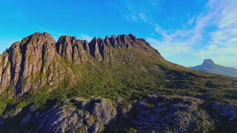 Towering mountain range with rugged peaks and green slopes under clear blue sky Stock Footage 345483081