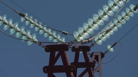 Towering power lines elegantly stretch across a vibrant bright blue sky Stock Footage 311281739