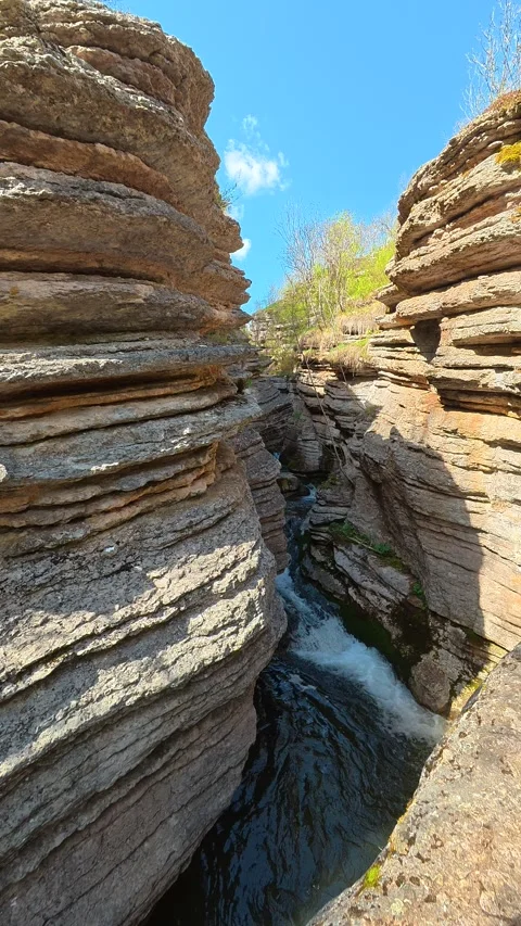 Towering rock walls frame a rushing stream. Rosomac Gorge, Vertical 库存影片 335947615