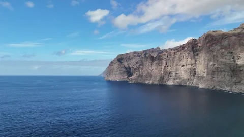 Towering Rugged Coastal Cliffs Above Blue Ocean Water Stock Footage 345576405