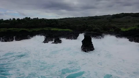 Towering waves engulf sea stacks on Hawaii’s volcanic coastline under moody Stock Footage 306126246