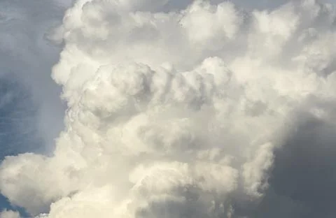 Towering white cloud forms dramatic texture in blue sky. Billowing cumulus ma Stock Photos
