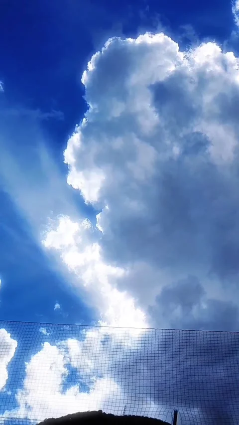 Towering white cumulus cloud against deep blue summer sky vertical video Stock Footage 340472315