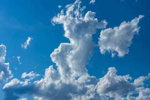 Towering white cumulus cloud rising in deep blue summer sky 库存照片
