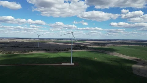 Towering wind turbines producing green energy built on an country cattle Stock Footage 248498941