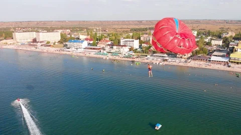 Towing red parachute behind a jetski over the sea along the beach at sunset. Stock Footage 118367707