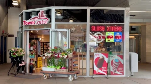 Town Centre Storefront with Slush Neon Sign and Flower Display - 4K Stock Footage 332930851