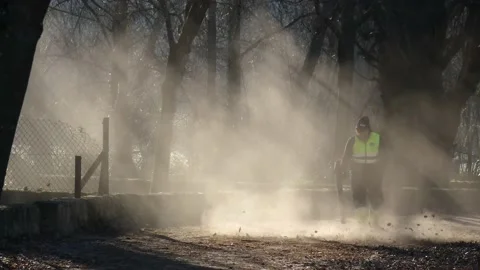 A town hall worker cleaning falling leaves on a city street in the autumn dry Stock Footage 234621557