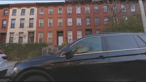 Town house and urban life on Brooklyn street on a Sunday from a traveling Stock Footage