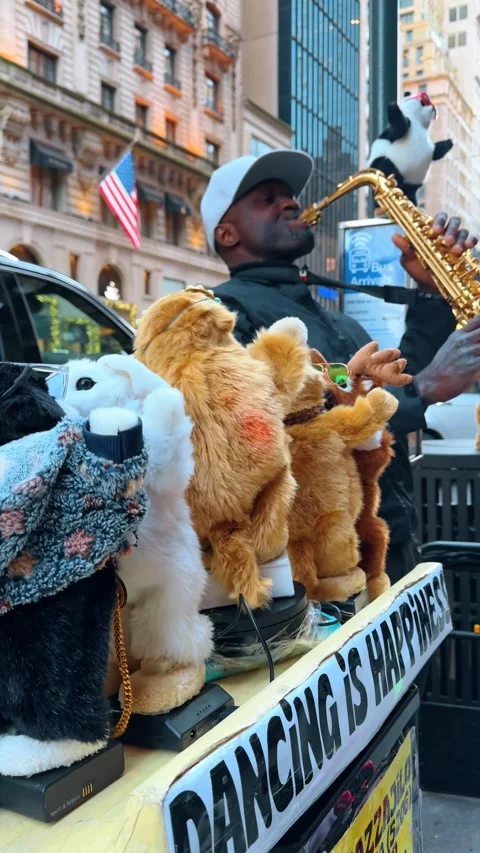 Toy animals dancing outdoors. Afro-American man is playing saxophone nearby in Stock Footage 328722165