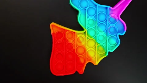 Toy antistress pop it in the shape of a unicorn spinning on a black background Stock Footage 156768408