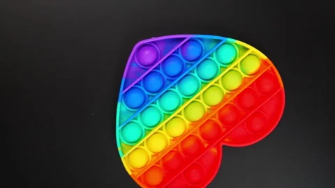 Toy antistress pop it in the shape of a heart spinning on a black background Stock Footage 156863864