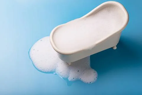Toy bath with flowing soap foam on a blue background. The concept of cleanlin Stock Photos