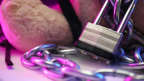 Toy bear chained with a lock in neon light Stock Footage 143523617