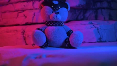 A toy bear dressed in a leather belt is an accessory for BDSM sex games in neon Stock Footage 202170238