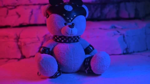 A toy bear dressed in a leather belt is an accessory for BDSM sex games in neon Stock Footage 202170249