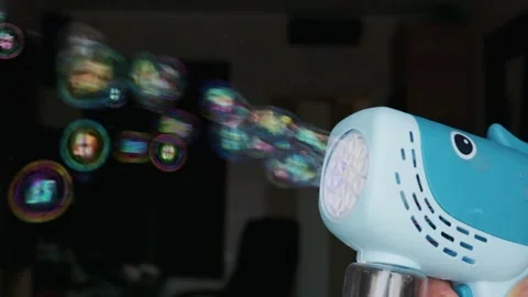 Toy Bubble Gun Blowing a Stream of Colorful Bubbles in Dark Room Stock Footage 339176640
