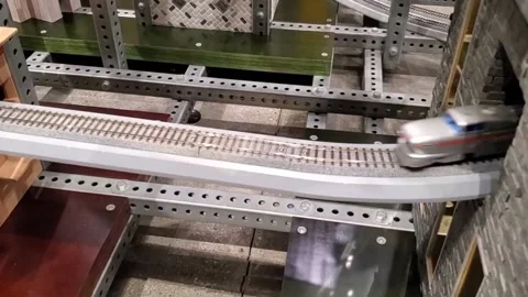 Toy bullet train racing through tunnel on train tracks Stock Footage 166716579