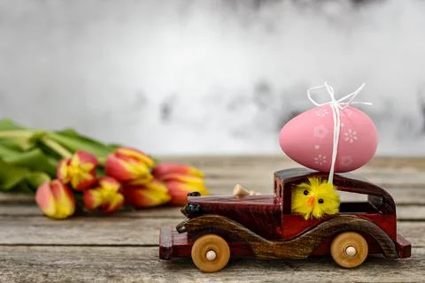 Toy car with an Easter egg and tulips Stock Photos